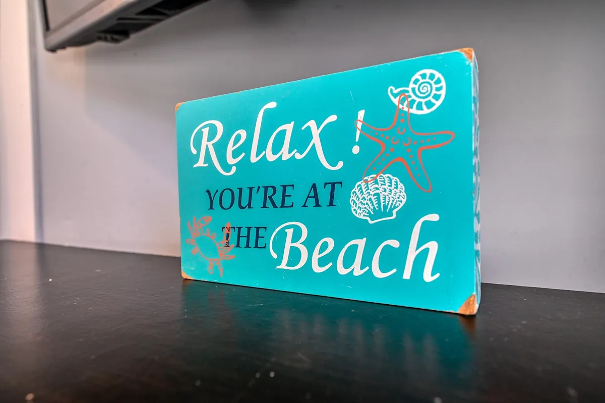 A cheerful, beach-themed sign displayed in a common area, evoking the spirit of fun and adventure associated with coastal living and vacation activities. The sign's design and setting suggest excitement for beach outings and shared family experiences.