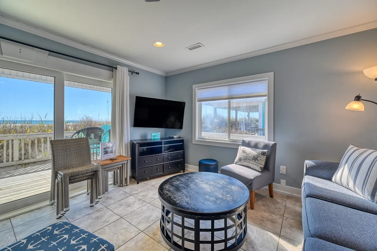 A spacious, comfortable seating area framed by large windows with a view, a stylish coffee table, and cozy ambiance. The scene suggests family relaxation, socializing, or soaking in sunrise views after local adventures.