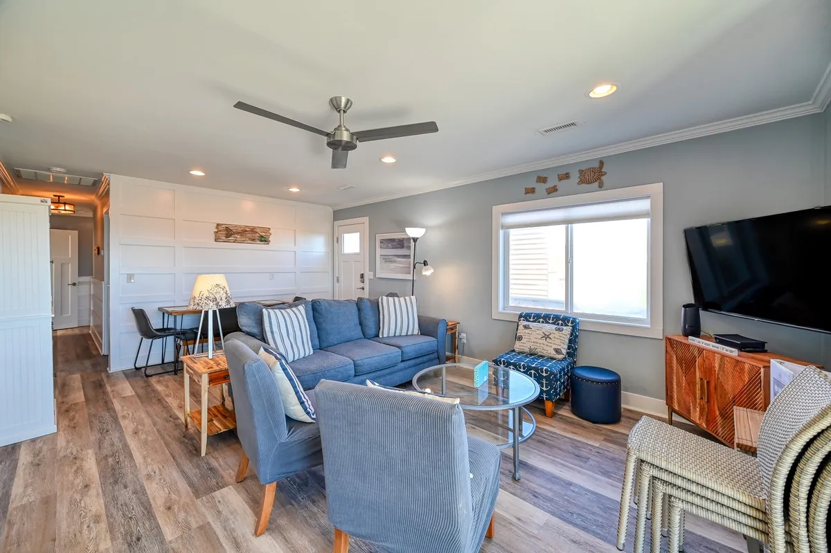 A cozy living and dining space with a plush sofa, coffee table, television, and adjoining dining area. Sunlight streams in, creating a welcoming environment ideal for both relaxation and group activities like family game nights or shared meals.
