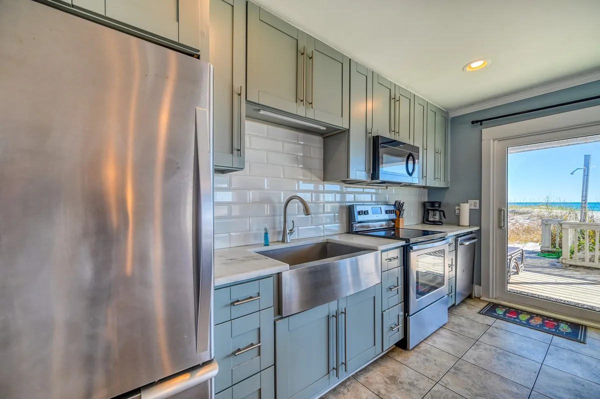 A stylish kitchen with stainless steel appliances and a large sink, featuring an open door that leads directly outside. The space is inviting and functional, ideal for cooking freshly caught seafood or entertaining family after a day of local attractions.