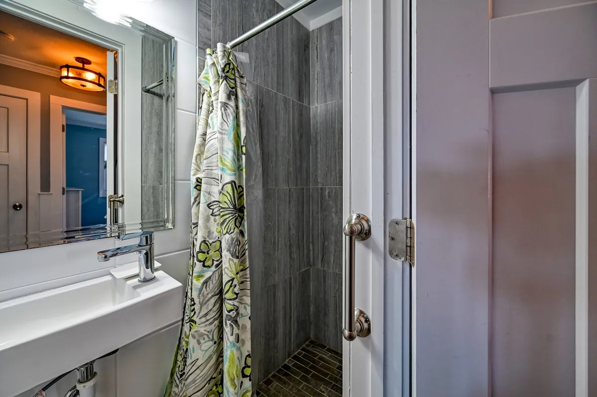 A modern bathroom featuring a well-lit shower area, stylish mirror, and sink. The fresh, clean environment is perfect for unwinding after a beach day or starting the morning routine.