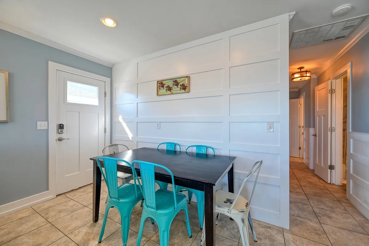 A dedicated dining area featuring a large table surrounded by metal chairs, classic wall paneling, and a welcoming doorway. The setup is ideal for family meals, celebrations, or intimate discussions, and the arrangement encourages togetherness.